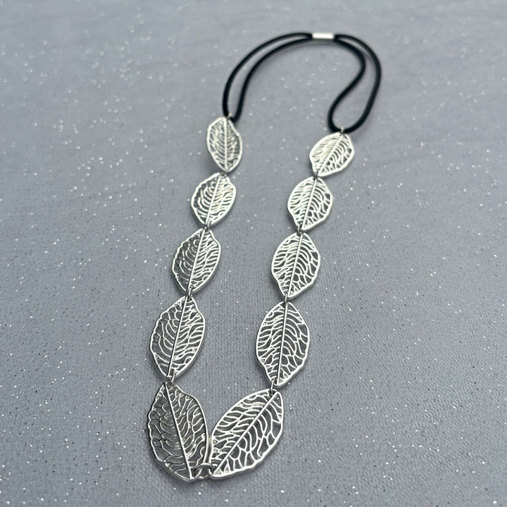 Leaf headband, silver tone metal leaves with cutout detailing, linked design, black elastic fastening for secure fit, nature inspired accessory, elegant vintage style headpiece, chic statement hairband, stylish gift for her