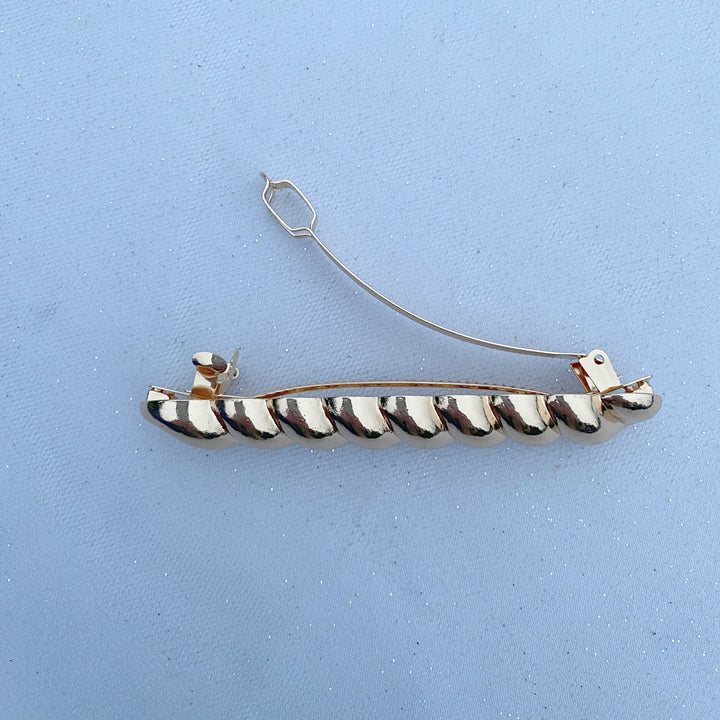 Gold barrette hair clasp, polished metallic finish, twisted bar design, strong clasp fastening, sleek minimalist style, decorative hair accessory