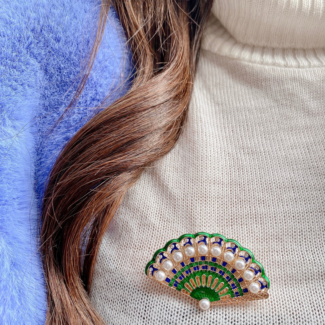 green brooch with pearls wedding guest