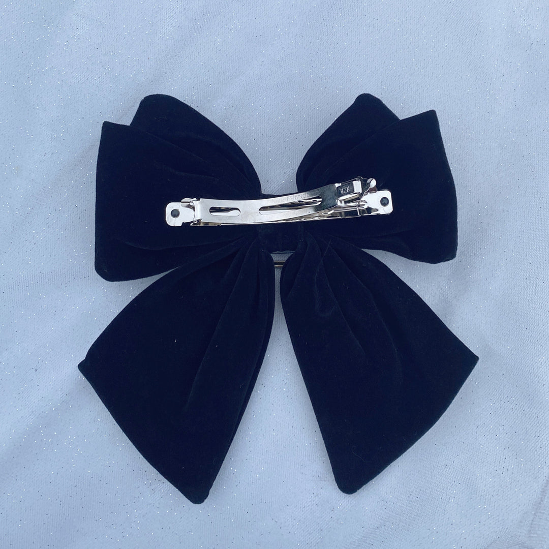 Large black velvet bow hair clip featuring a sparkly jeweled buckle.