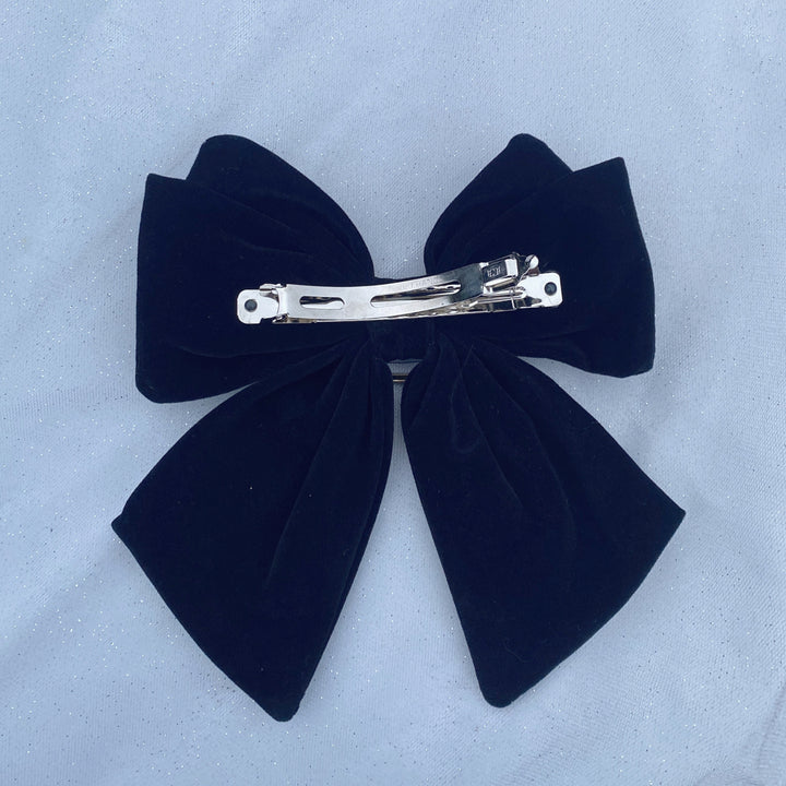 Large black velvet bow hair clip featuring a sparkly jeweled buckle.