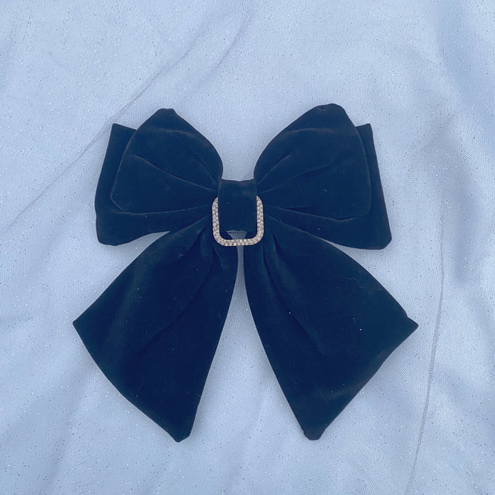 Large black velvet bow hair clip featuring a sparkly jeweled buckle.