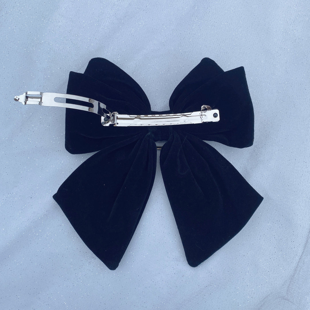 Large black velvet bow hair clip featuring a sparkly jeweled buckle.