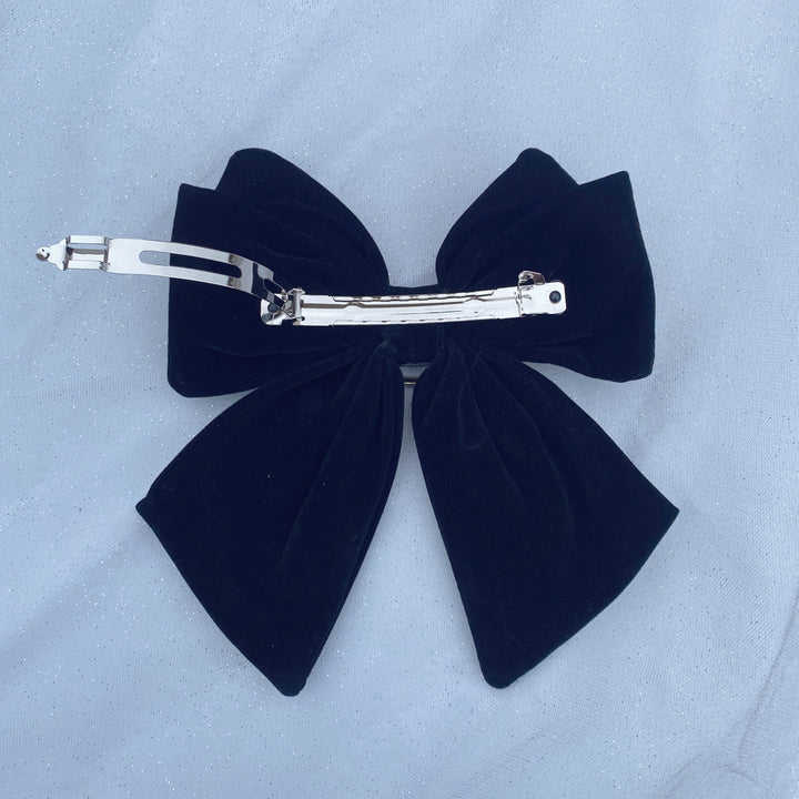 Large black velvet bow hair clip featuring a sparkly jeweled buckle.