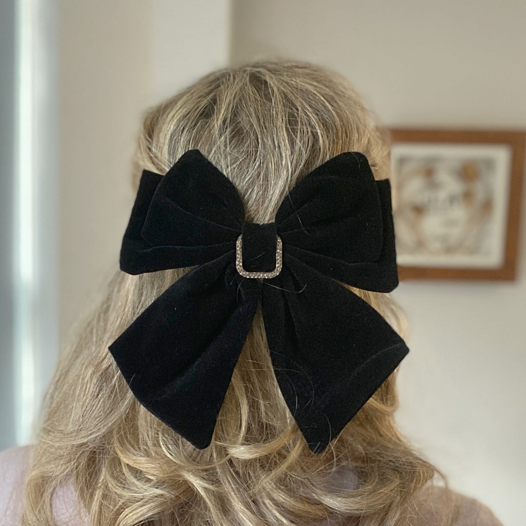 Large black velvet bow hair clip featuring a sparkly jeweled buckle.