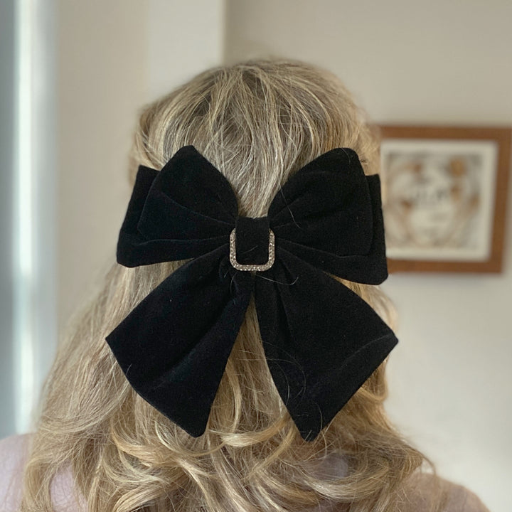 Large black velvet bow hair clip featuring a sparkly jeweled buckle.