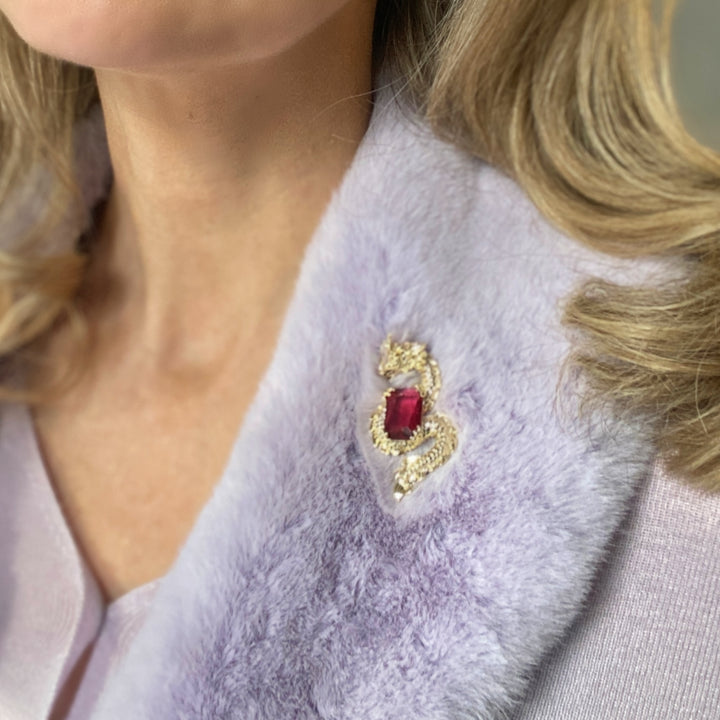 Gold dragon brooch wrapped around a large red gemstone.