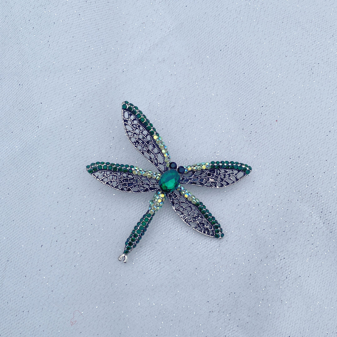 Green crystal dragonfly brooch with lace-style wings and an emerald centre stone.