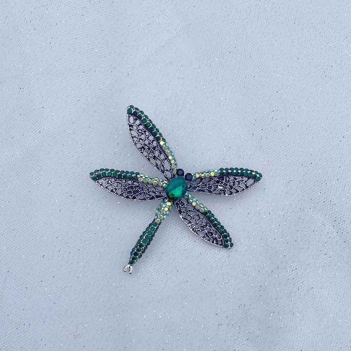 Green crystal dragonfly brooch with lace-style wings and an emerald centre stone.