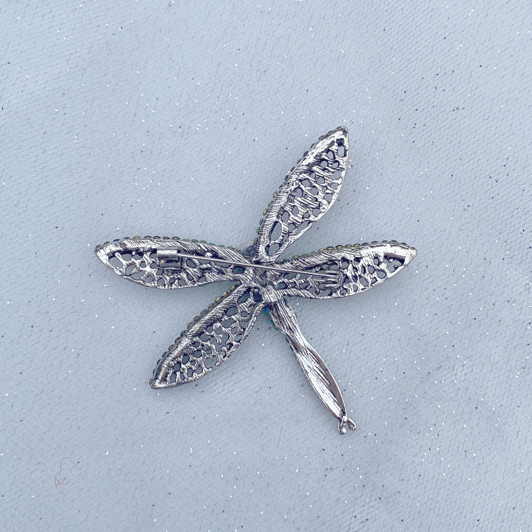 Green crystal dragonfly brooch with lace-style wings and an emerald centre stone.