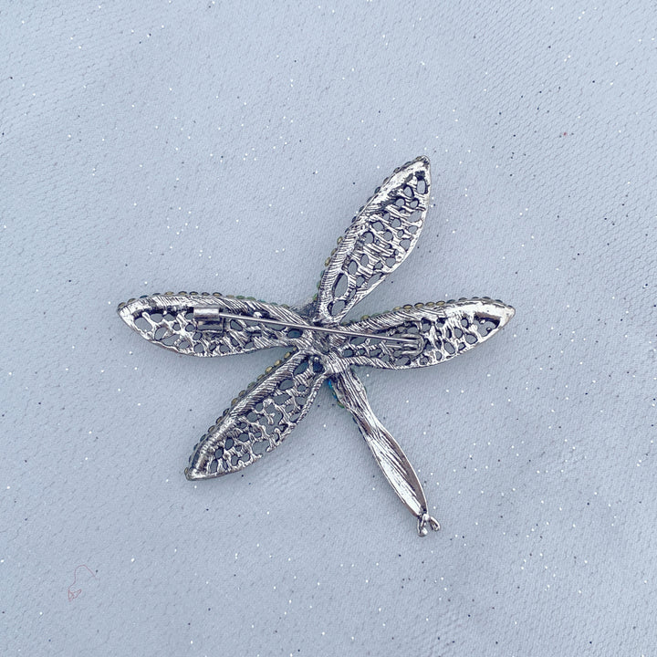 Green crystal dragonfly brooch with lace-style wings and an emerald centre stone.