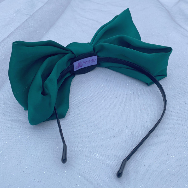 Green oversized bow fascinator on a thin black headband.