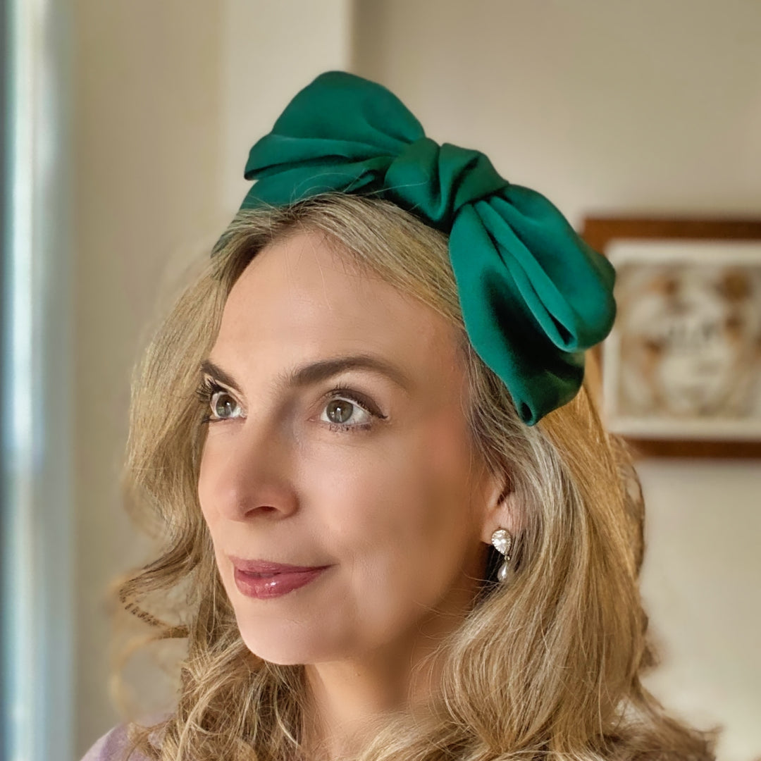 Green oversized bow fascinator on a thin black headband.