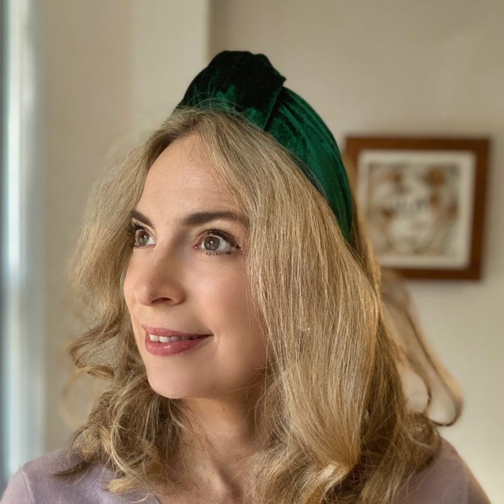 Green velvet knot headband with a wide, padded design on a white fabric background.
