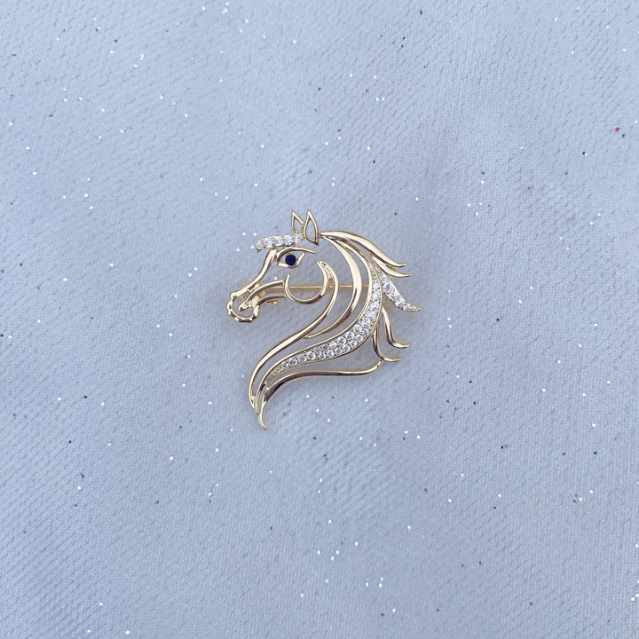 Gold horse head brooch with crystal detailing and a dark stone eye.