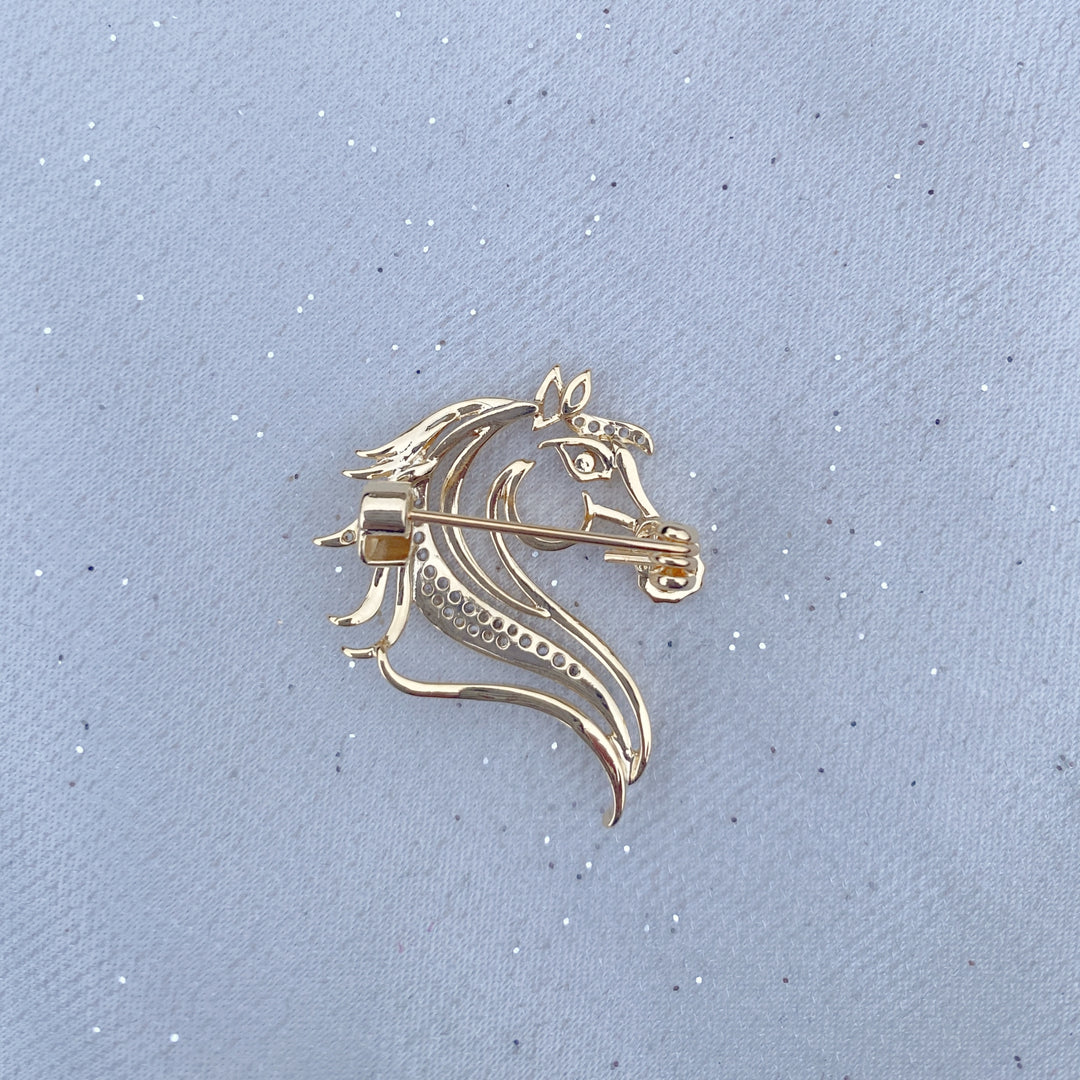 Gold horse head brooch with crystal detailing and a dark stone eye.