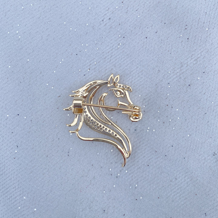 Gold horse head brooch with crystal detailing and a dark stone eye.
