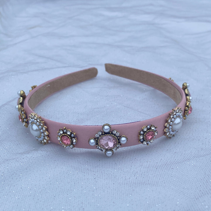 Pink headband decorated with pearl and crystal floral embellishments.