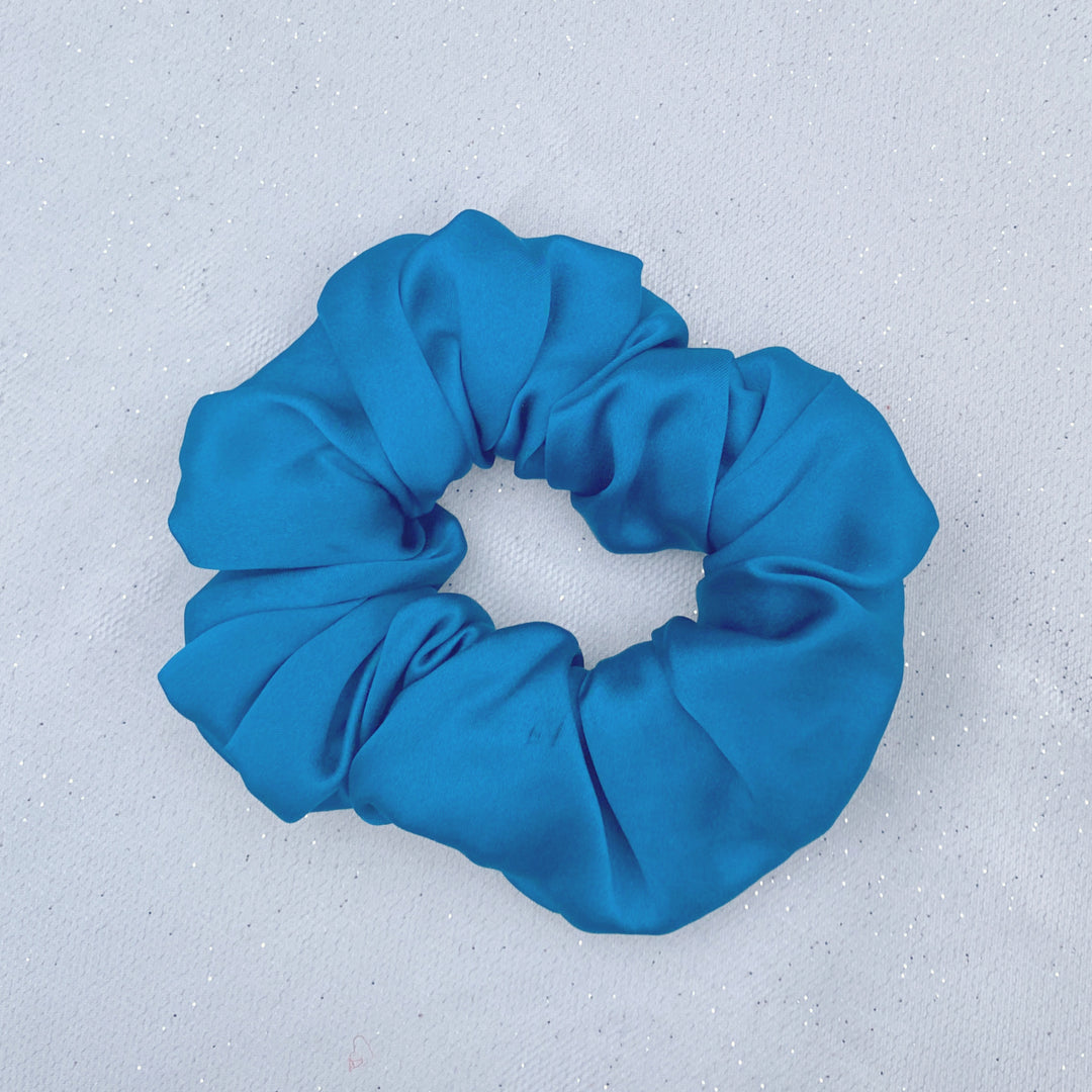Teal silk scrunchie with a softly gathered, smooth satin texture.